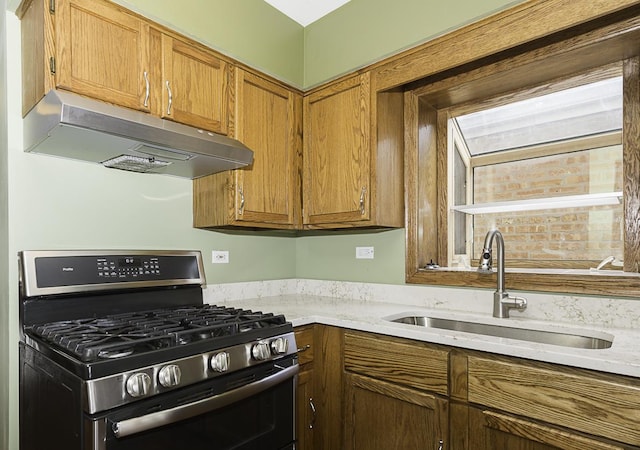 kitchen featuring brown cabinetry, stainless steel range with gas cooktop, a sink, and under cabinet range hood