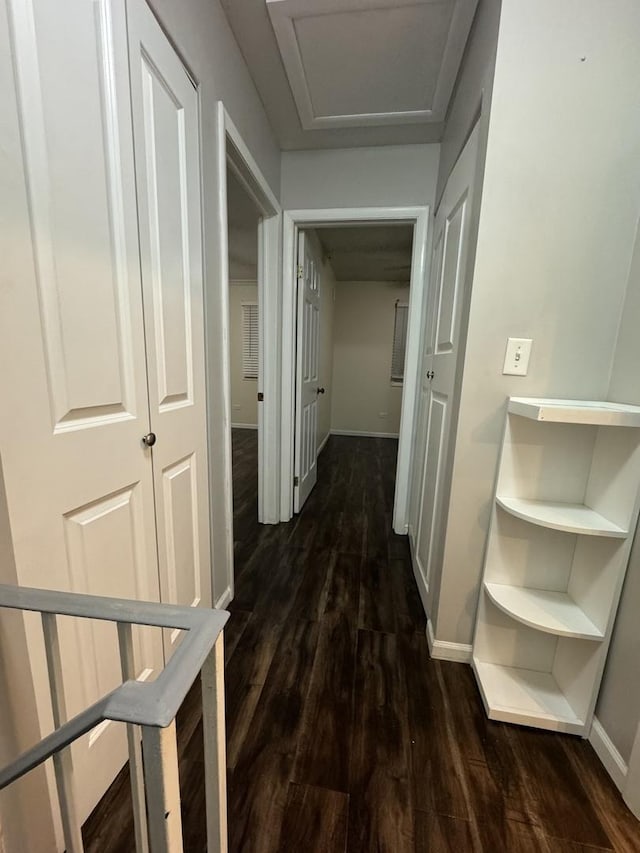 hallway with attic access, dark wood-style floors, and baseboards