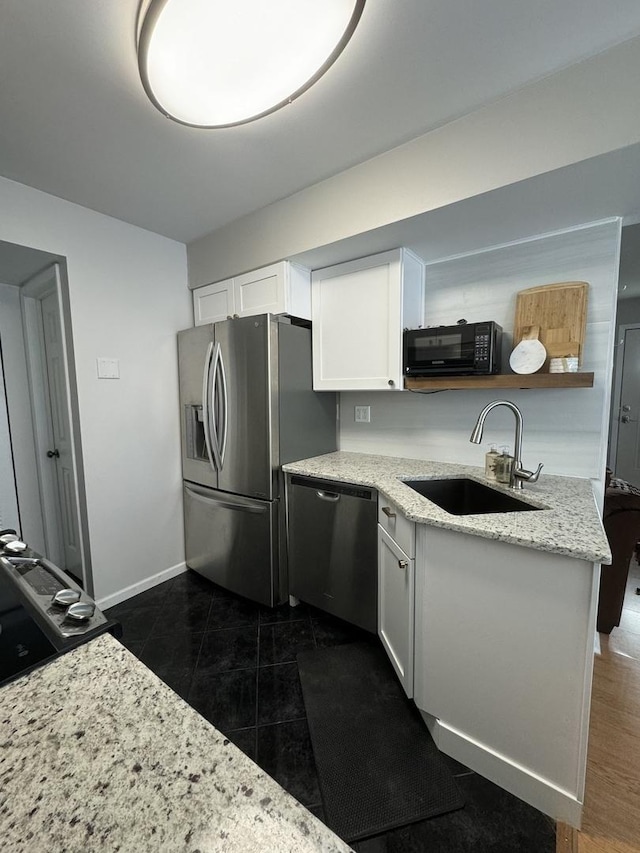 kitchen featuring a sink, light stone countertops, white cabinets, stainless steel appliances, and open shelves