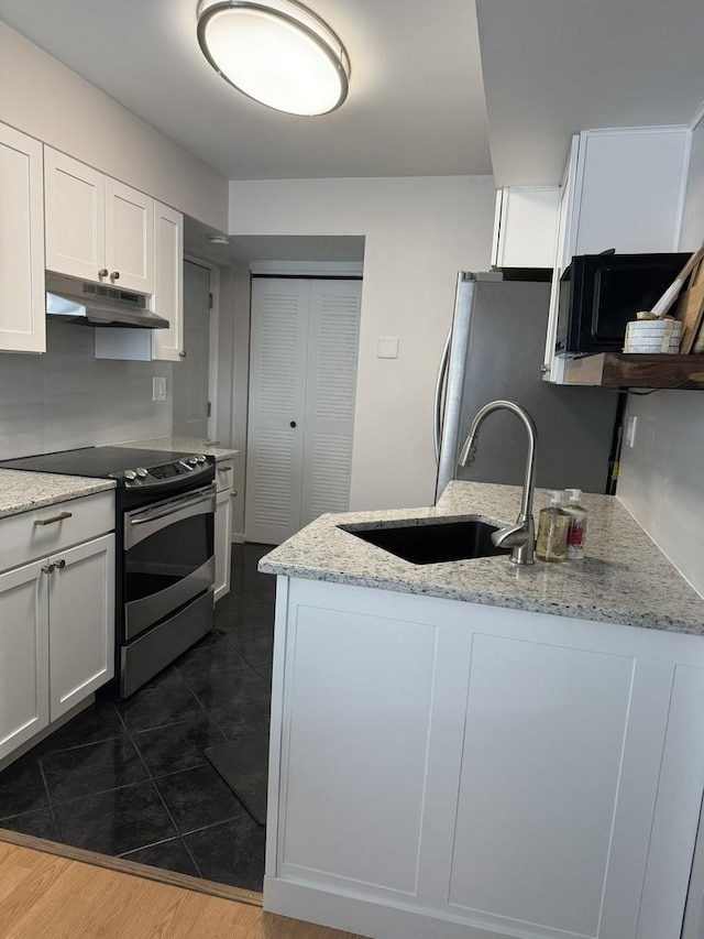 kitchen featuring light stone countertops, a sink, under cabinet range hood, appliances with stainless steel finishes, and white cabinetry