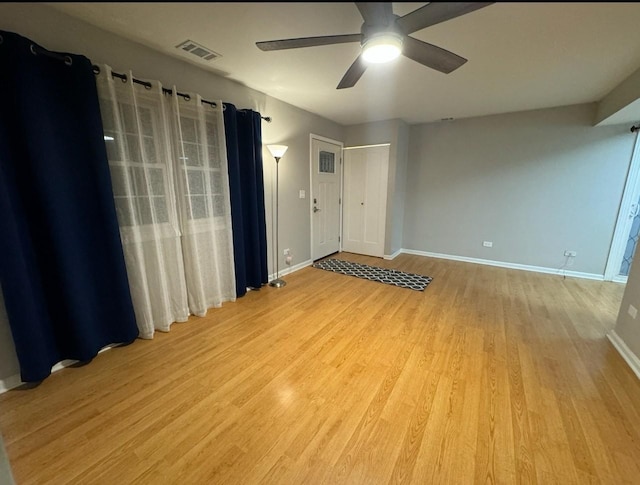 unfurnished room with a ceiling fan, visible vents, baseboards, and light wood-type flooring