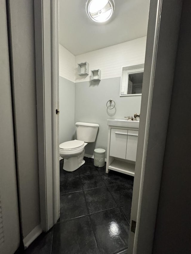 half bath featuring tile patterned floors, toilet, and vanity