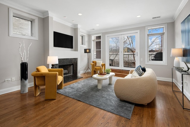 sitting room with crown molding, visible vents, a premium fireplace, wood finished floors, and baseboards