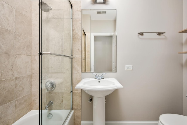 bathroom with toilet, shower / bath combination with glass door, baseboards, and visible vents