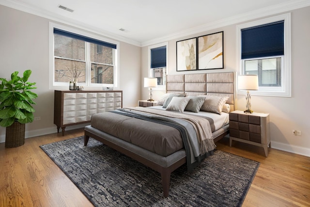 bedroom featuring baseboards, visible vents, wood finished floors, and ornamental molding