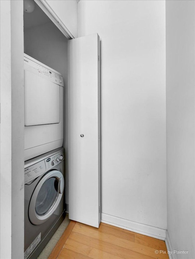 laundry room with laundry area, light wood-type flooring, and stacked washer and clothes dryer