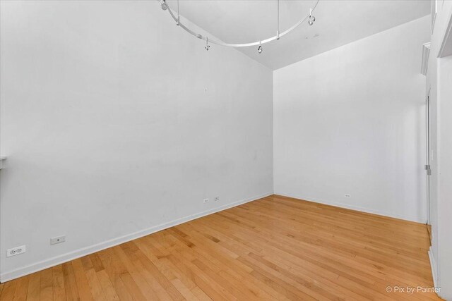 unfurnished room featuring light wood finished floors, attic access, and baseboards