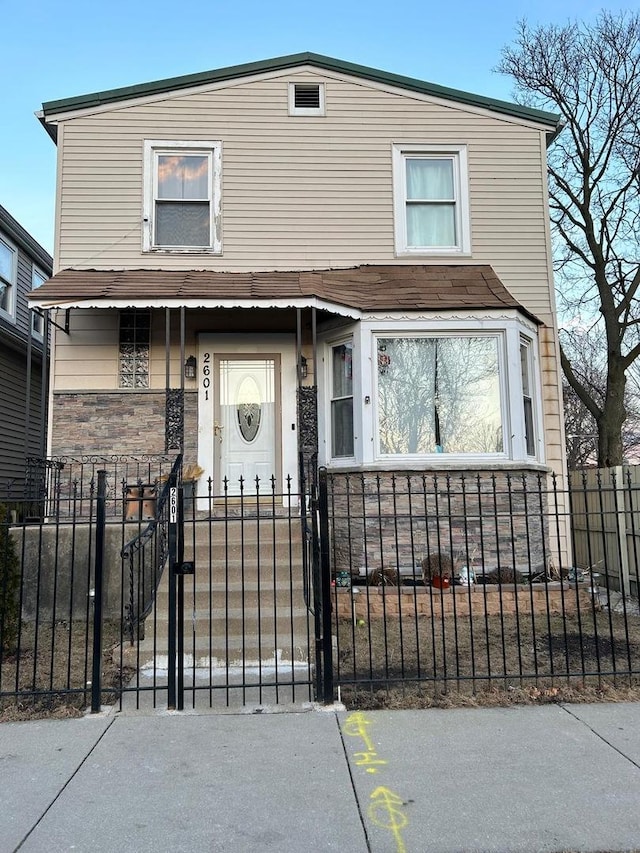 view of front of house featuring a gate, stone siding, and a fenced front yard