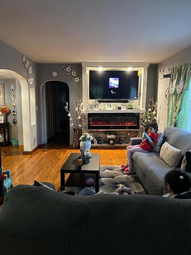 living room featuring a fireplace, wood finished floors, and arched walkways