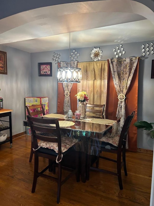 dining room featuring baseboards, arched walkways, and wood finished floors