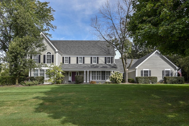 view of front of house with roof with shingles and a front yard