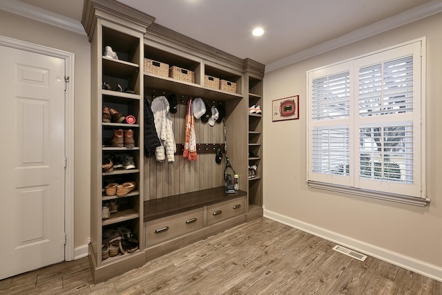 mudroom featuring ornamental molding, visible vents, baseboards, and wood finished floors