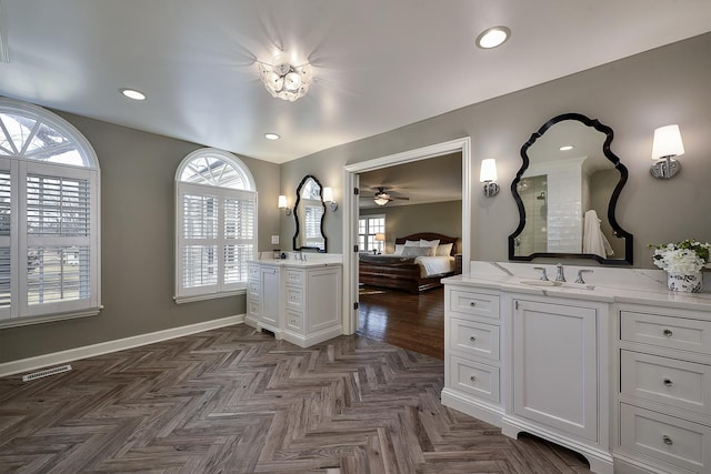 ensuite bathroom with a healthy amount of sunlight, baseboards, visible vents, and two vanities