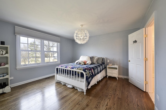 bedroom with dark wood-style flooring, baseboards, and an inviting chandelier