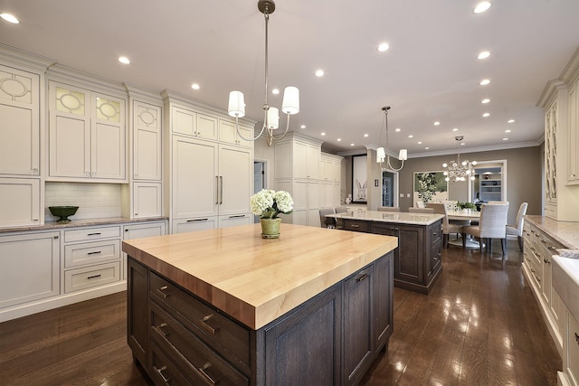 kitchen with white cabinets, wood counters, dark wood-type flooring, a center island, and dark brown cabinets