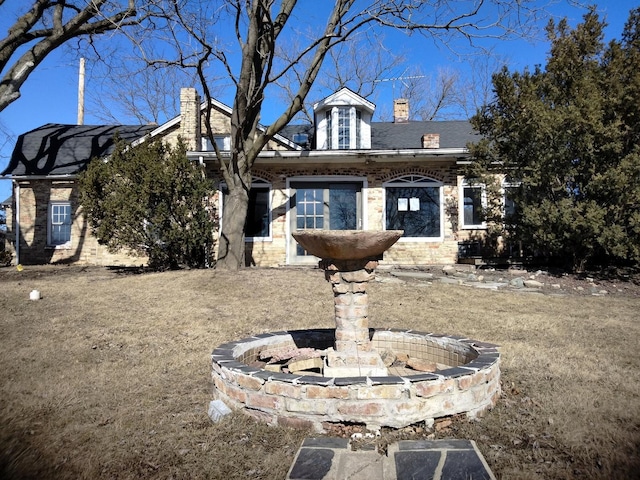 view of front of home with stone siding and a chimney