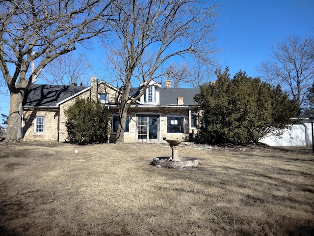 view of front of house with brick siding, a chimney, and a front yard