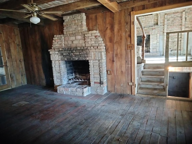 unfurnished living room with beam ceiling, wood-type flooring, wood walls, and ceiling fan