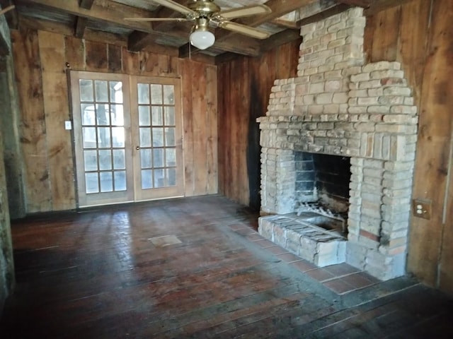 unfurnished living room with wooden walls, beamed ceiling, french doors, hardwood / wood-style flooring, and a ceiling fan