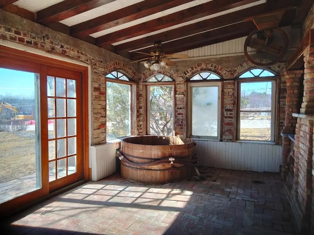 unfurnished sunroom featuring beam ceiling and a ceiling fan