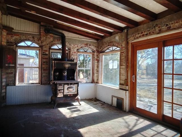 unfurnished sunroom with lofted ceiling with beams and a wood stove