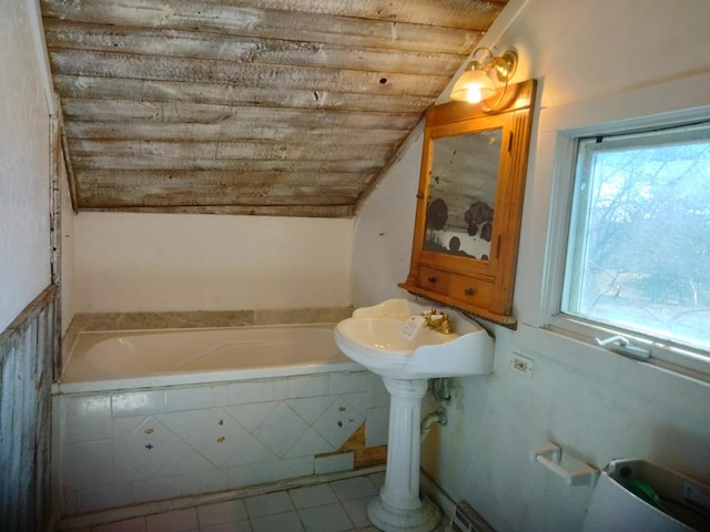 bathroom featuring tiled bath, tile patterned floors, and vaulted ceiling