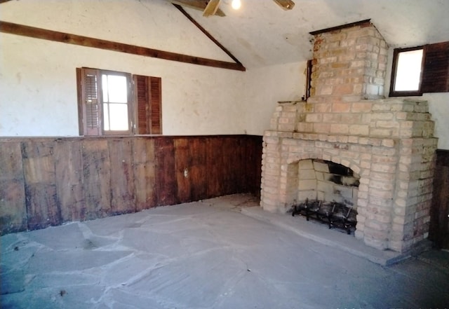 unfurnished living room with wainscoting, wood walls, and vaulted ceiling