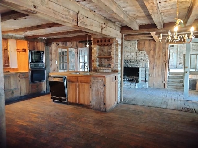 kitchen with wooden walls, dark wood-style flooring, black appliances, beamed ceiling, and a notable chandelier