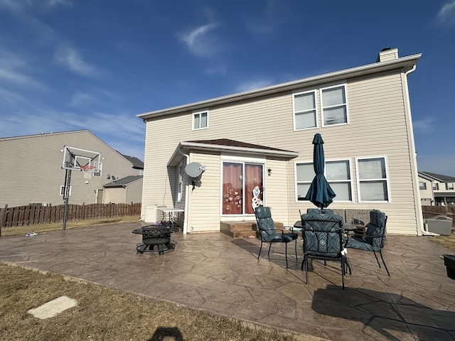 back of house with a chimney, a patio, a fire pit, and fence