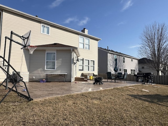 back of house with a patio area, a lawn, a chimney, and fence