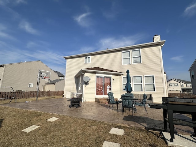 rear view of house featuring entry steps, an outdoor fire pit, a chimney, fence, and a patio area