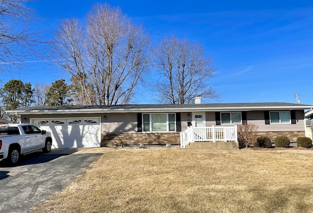 ranch-style home with driveway, a chimney, an attached garage, a front lawn, and brick siding