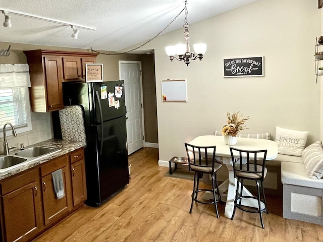 kitchen featuring vaulted ceiling, light wood-type flooring, a sink, and freestanding refrigerator