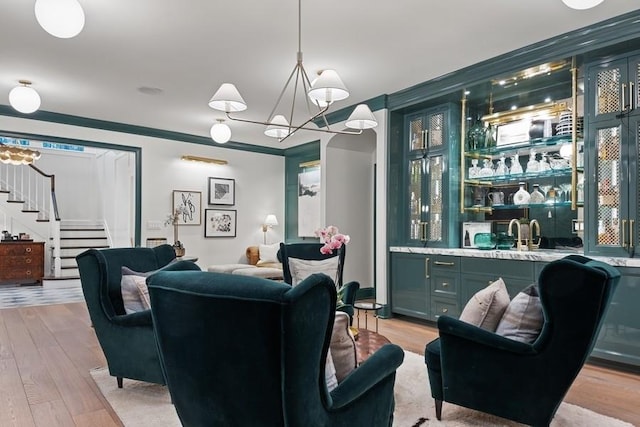 bar featuring light wood-style flooring, decorative light fixtures, a sink, stairway, and indoor wet bar