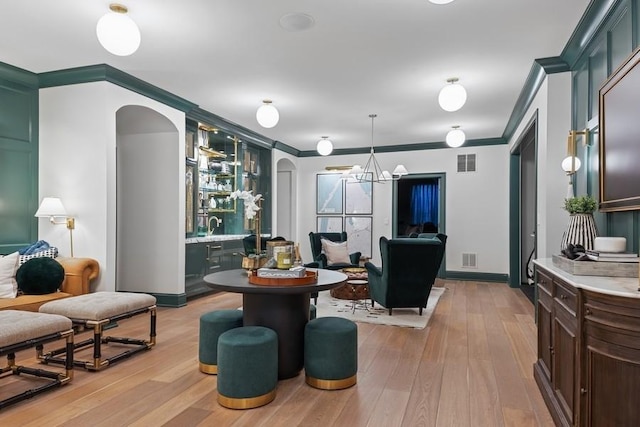 interior space with light wood-type flooring, visible vents, arched walkways, and crown molding