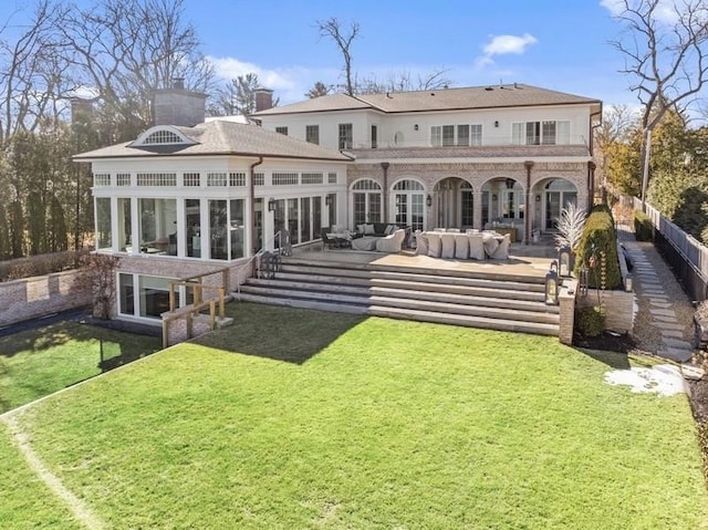 back of house featuring a lawn, an outdoor living space, a patio, fence, and a sunroom