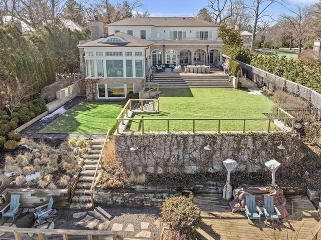 rear view of property featuring a deck, a lawn, a fenced backyard, and a chimney