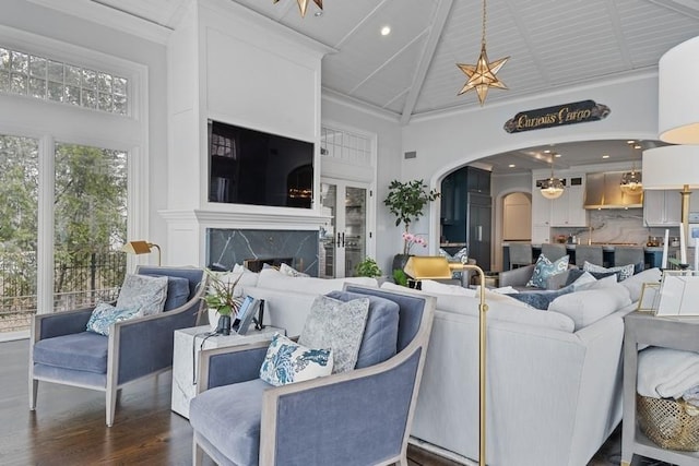 living room featuring a fireplace, arched walkways, dark wood-style flooring, and high vaulted ceiling