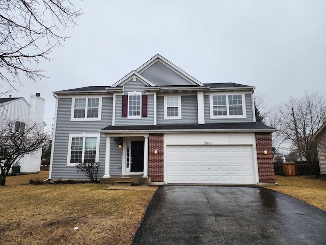 traditional-style house with brick siding, a garage, a front lawn, and driveway