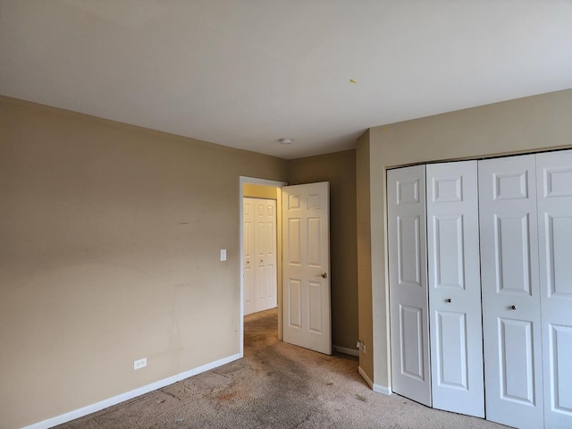 unfurnished bedroom with a closet, baseboards, and carpet