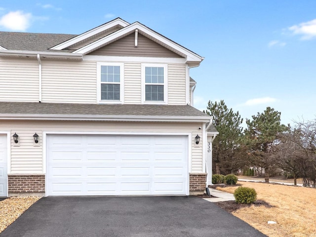 view of front of house featuring aphalt driveway, brick siding, and a shingled roof