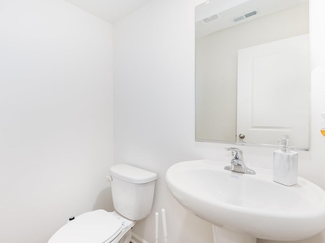 bathroom featuring visible vents, toilet, and a sink