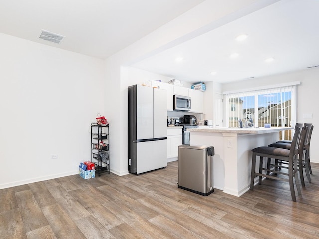 kitchen with a breakfast bar, light wood-type flooring, visible vents, and stainless steel appliances