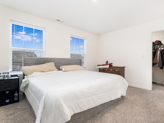 bedroom featuring visible vents, a walk in closet, baseboards, carpet, and a closet