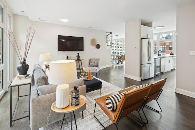 living room featuring dark wood-style floors, wine cooler, baseboards, and stairs