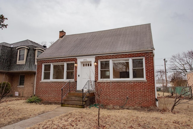 view of front of home with roof with shingles, a chimney, fence, and brick siding