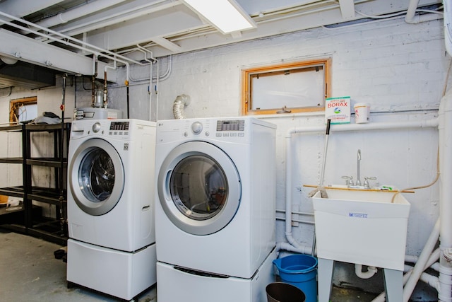 clothes washing area with laundry area, a sink, and independent washer and dryer