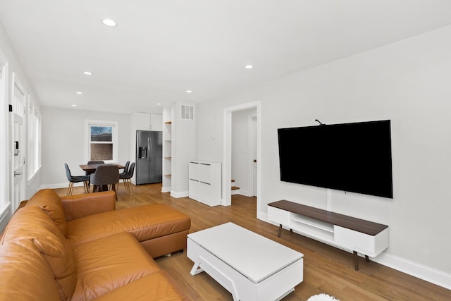 living room featuring baseboards, recessed lighting, visible vents, and light wood-style floors