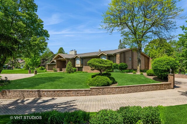 view of front of home with brick siding, a chimney, and a front yard