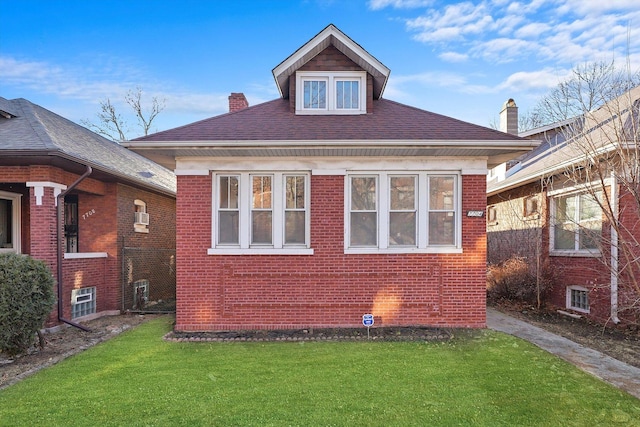 view of side of home with brick siding, a chimney, a yard, and a shingled roof